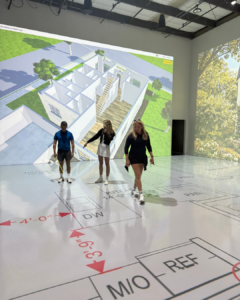 Three clients walk through their full-scale home floor plan at Walk Your Plans Tampa, exploring room layouts and dimensions with immersive 3D architectural projections.